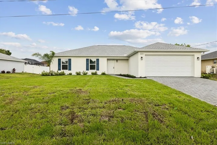 Single story home featuring a garage and a front lawn
