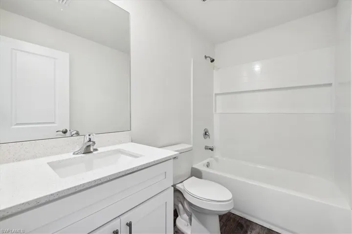 Full bathroom with vanity, toilet, hardwood / wood-style flooring, and bathtub / shower combination