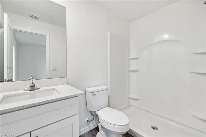Bathroom with walk in shower, toilet, hardwood / wood-style flooring, and vanity