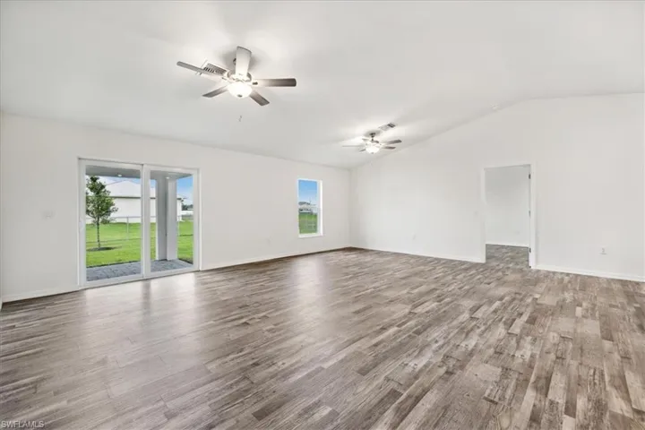 Unfurnished living room featuring ceiling fan, wood-type flooring, and vaulted ceiling