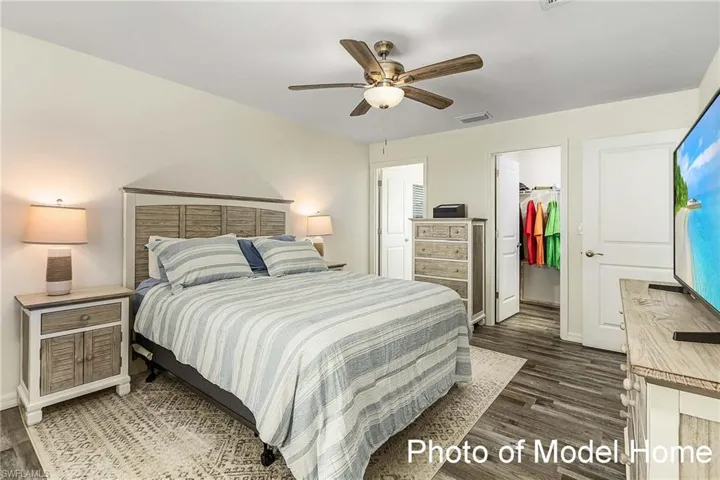 Bedroom featuring dark wood-type flooring, ceiling fan, a walk in closet, and a closet