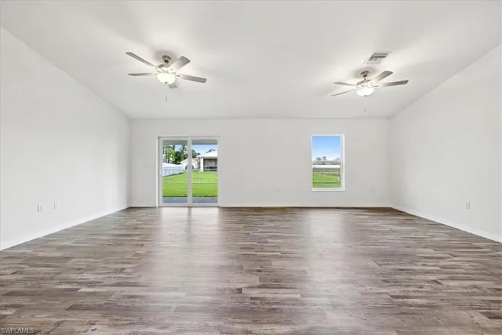 Unfurnished room featuring a wealth of natural light, ceiling fan, dark hardwood / wood-style flooring, and lofted ceiling