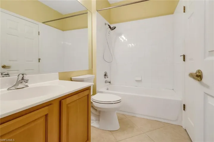 Full guest bathroom featuring tiled shower / bath combo, vanity, toilet, and tile patterned flooring