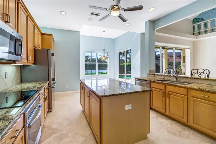 Kitchen featuring appliances with stainless steel finishes, a kitchen island, tasteful backsplash, and light tile patterned flooring