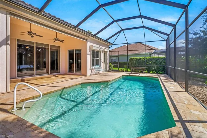View of pool with two ceiling fans over the lanai area and screen enclosure
