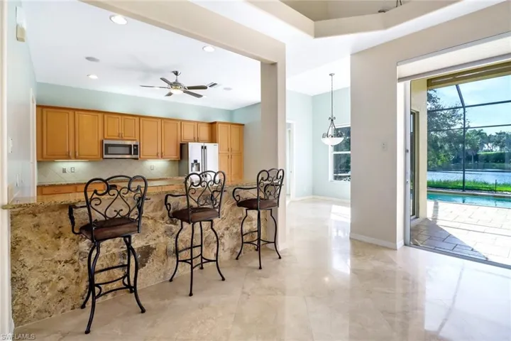 Kitchen with light tile patterned floors, a breakfast bar area, stainless steel appliances, and ceiling fan