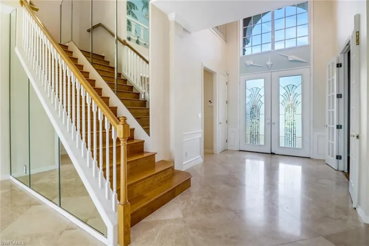 Foyer featuring a towering ceiling, light tile patterned flooring, and french doors