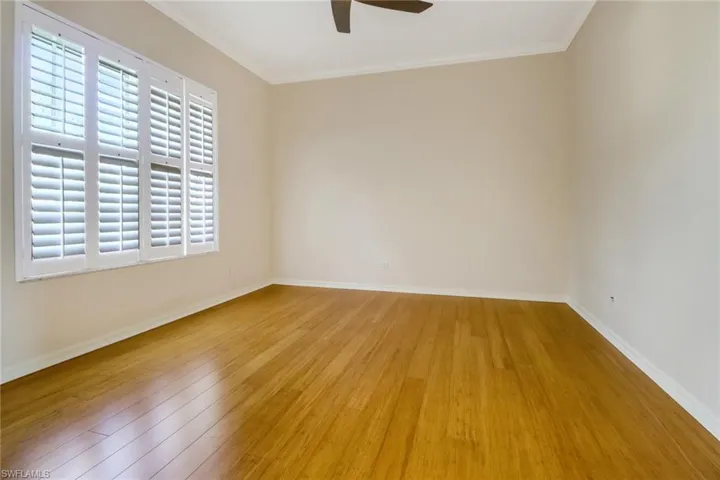 Den with crown molding, plenty of natural light, Bamboo wood-style flooring, ceiling fan and French doors.