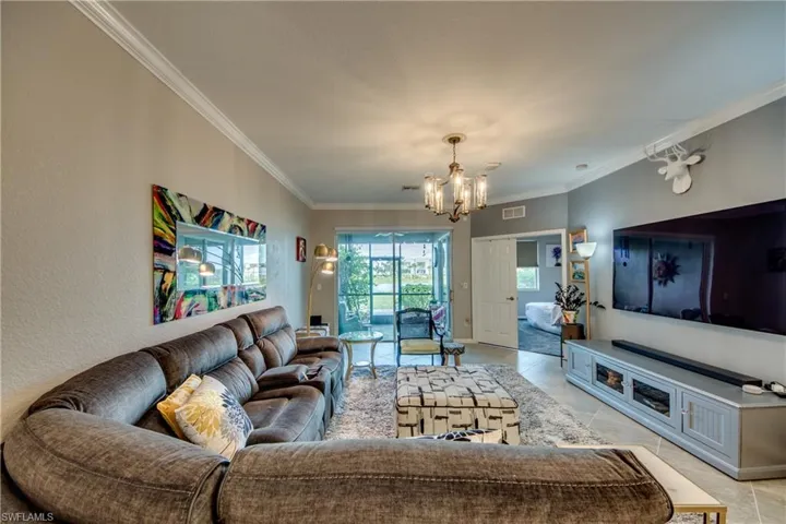 Living room featuring a chandelier, light tile patterned floors, and ornamental molding