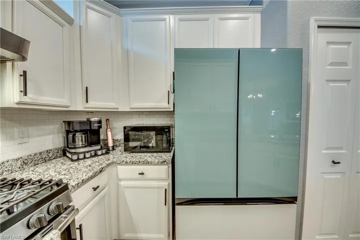Kitchen featuring white cabinets, ventilation hood, and fridge