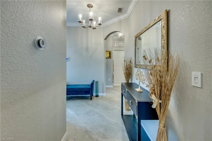 Corridor featuring ornamental molding and an inviting chandelier