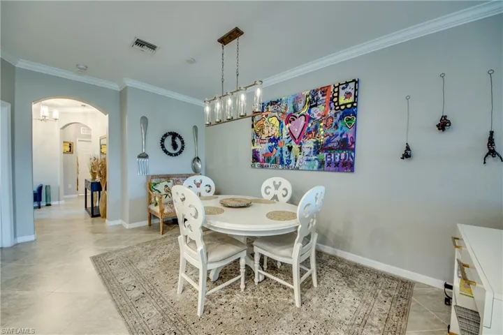 Dining area with light tile patterned floors and crown molding