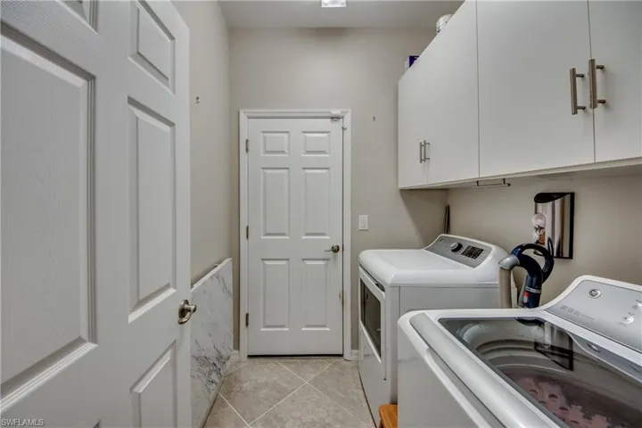 Clothes washing area featuring cabinets, independent washer and dryer, and light tile patterned floors
