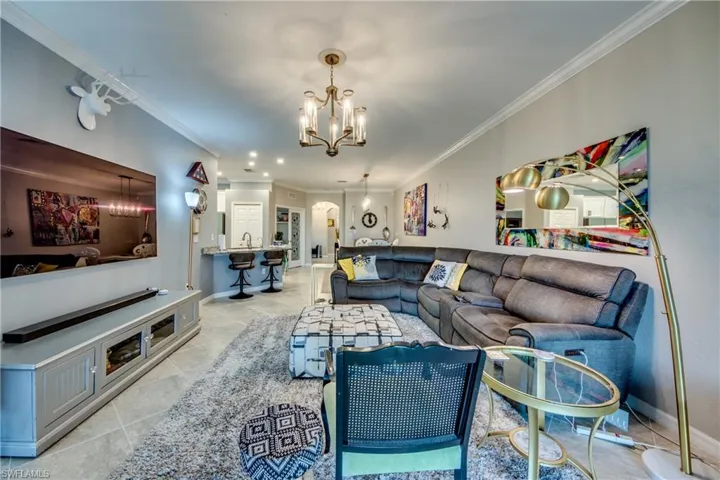 Living room featuring an inviting chandelier, ornamental molding, and light tile patterned flooring