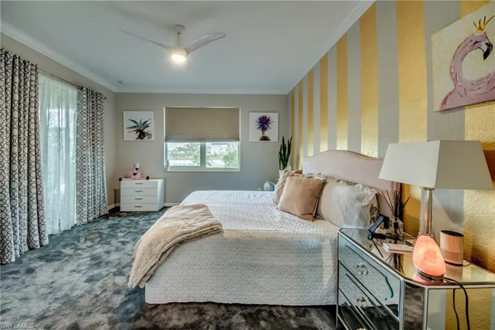 Bedroom featuring multiple windows, dark carpet, ceiling fan, and ornamental molding