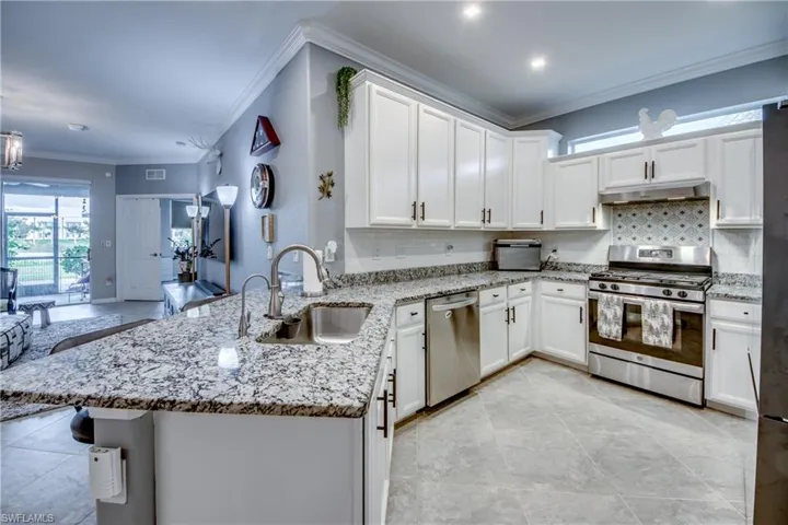 Kitchen with kitchen peninsula, crown molding, sink, and stainless steel appliances