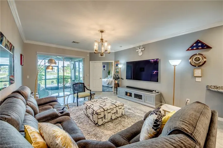 Living room with an inviting chandelier, ornamental molding, and light tile patterned flooring