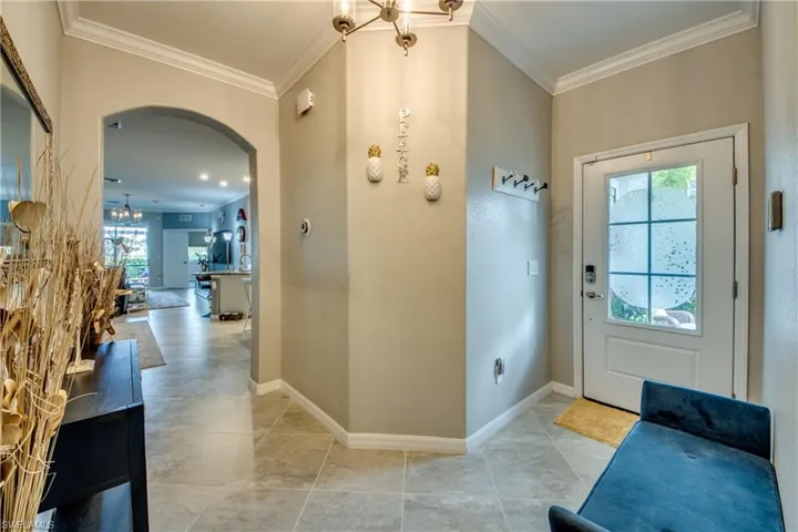 Entryway with a wealth of natural light, crown molding, and a notable chandelier