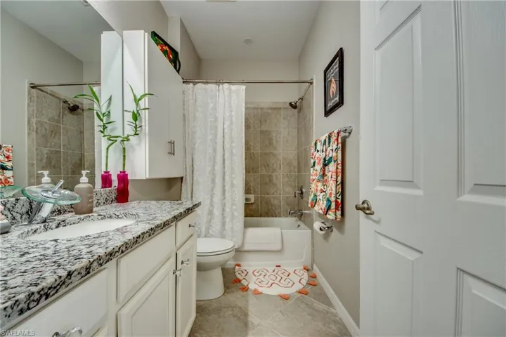 Full bathroom with tile patterned floors, vanity, toilet, and shower / bathtub combination with curtain