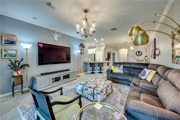 Tiled living room featuring a notable chandelier and crown molding