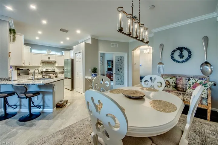 Tiled dining area with sink, an inviting chandelier, and ornamental molding