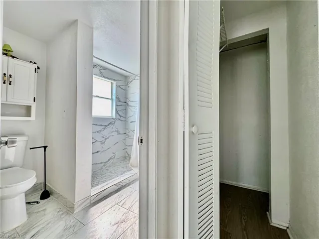 Full bath featuring a marble finish shower and toilet