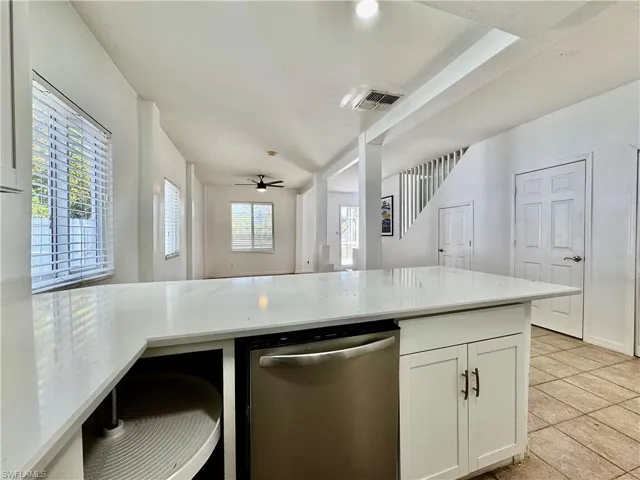 Kitchen featuring dishwasher, light stone countertops, white cabinetry, open floor plan, and a ceiling fan