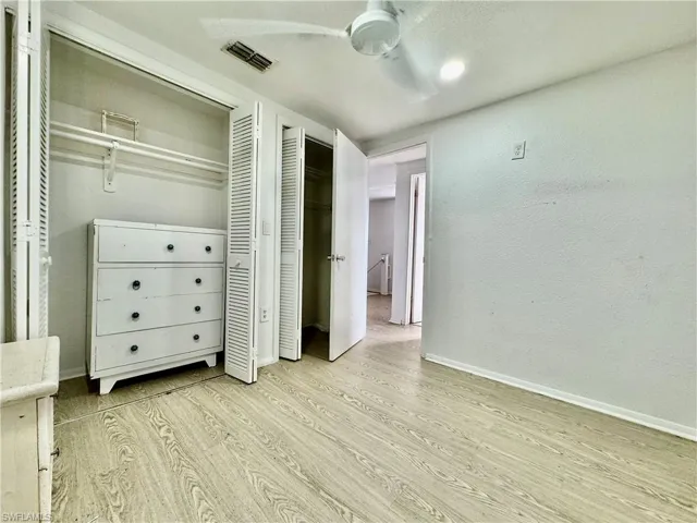 Bedroom featuring light wood-style floors, a closet, a ceiling fan, and a textured wall