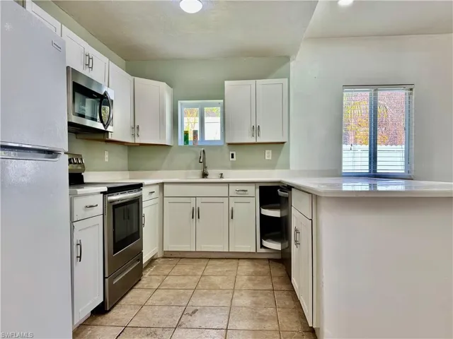 Kitchen featuring stainless steel appliances, white cabinetry, a peninsula, and light tile patterned floors