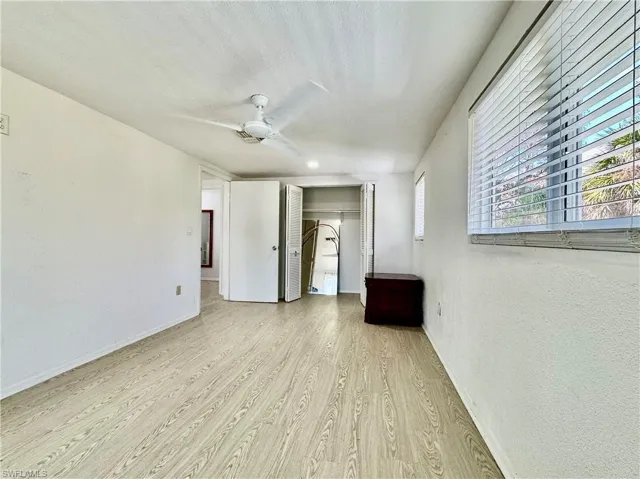 Unfurnished bedroom with light wood-type flooring, a ceiling fan, a textured wall, and a closet