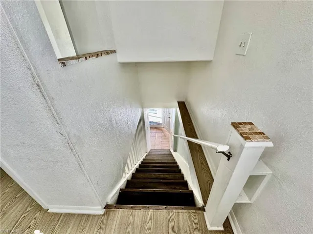 Stairway featuring a textured wall and wood finished floors