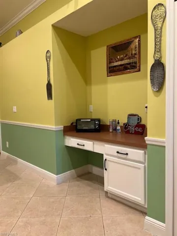 Unfurnished office featuring built in study area, baseboards, light tile patterned flooring, and ornamental molding