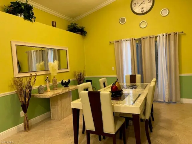 Tiled dining room with ornamental molding and baseboards