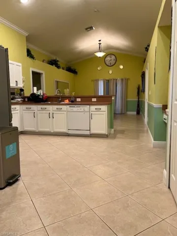 Kitchen with dishwasher, refrigerator, crown molding, dark countertops, and light tile patterned floors