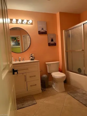 Bathroom featuring toilet, tile patterned flooring, vanity, and combined bath / shower with glass door
