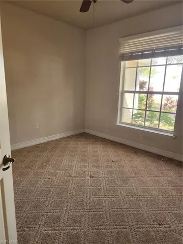 Carpeted spare room with ceiling fan and baseboards