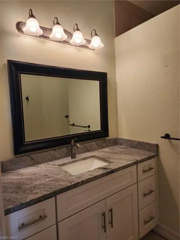 Bathroom featuring a textured wall and vanity