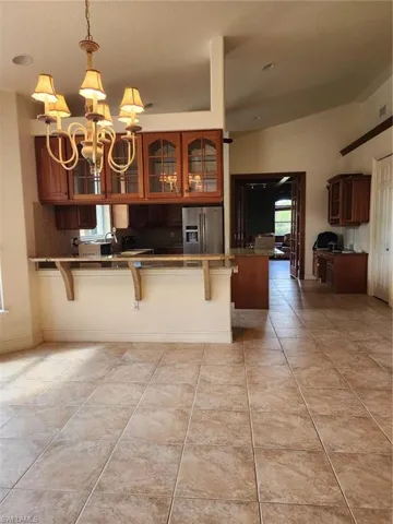 Kitchen with a breakfast bar, suspended lighting, fridge, and wood finish cabinetry