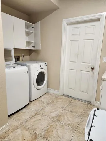 Laundry area featuring cabinet space, separate washer and dryer, and light tile patterned floors