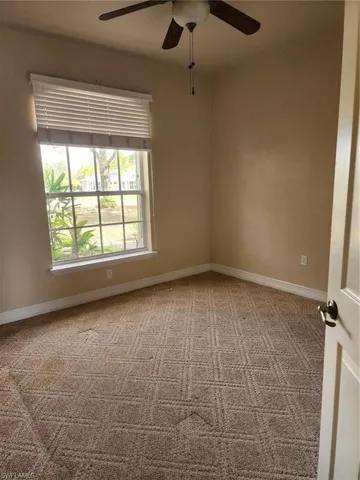 Empty room with a ceiling fan and light carpet