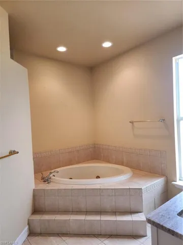 Full bath with a tub with jets, recessed lighting, light tile patterned floors, and vanity