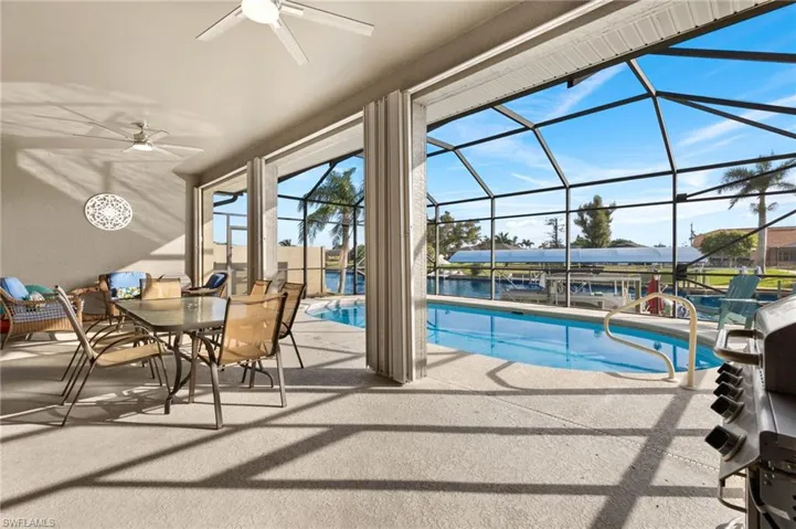 View of pool with screened in lanai and ceiling fans