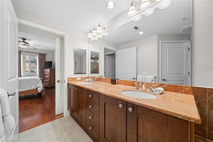 Full bathroom with double vanity, ensuite bathroom, and light tile patterned floors
