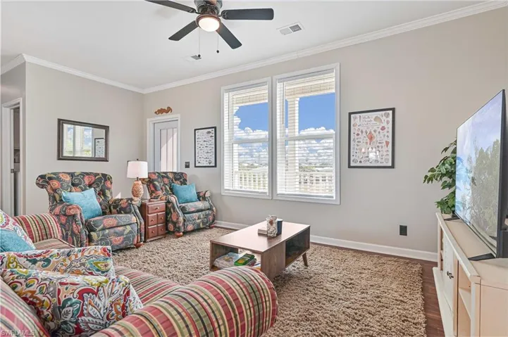Living room featuring crown molding, wood finished floors, and a ceiling fan
