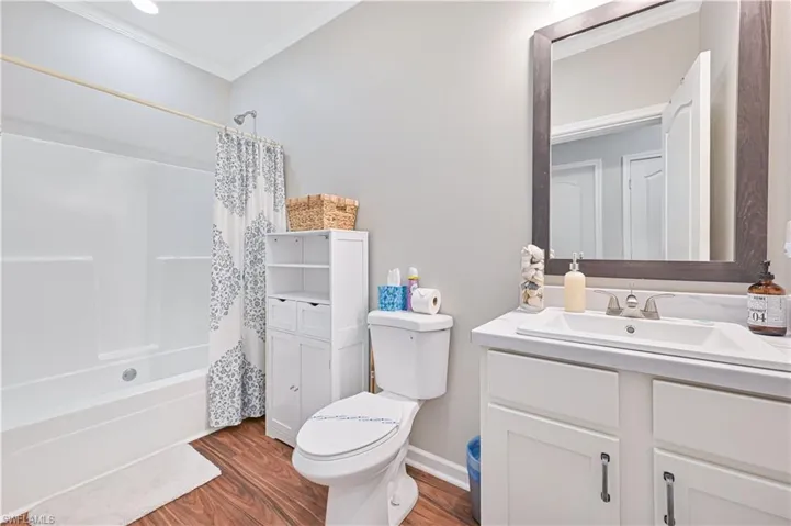 Full bathroom with vanity, shower / bath combo, crown molding, and wood finished floors