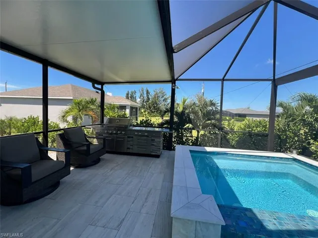 View of swimming pool with a sunroom, glass enclosure, a pool, and an outdoor kitchen