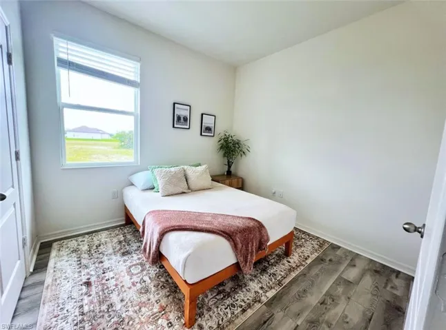 Bedroom with wood finished floors and baseboards