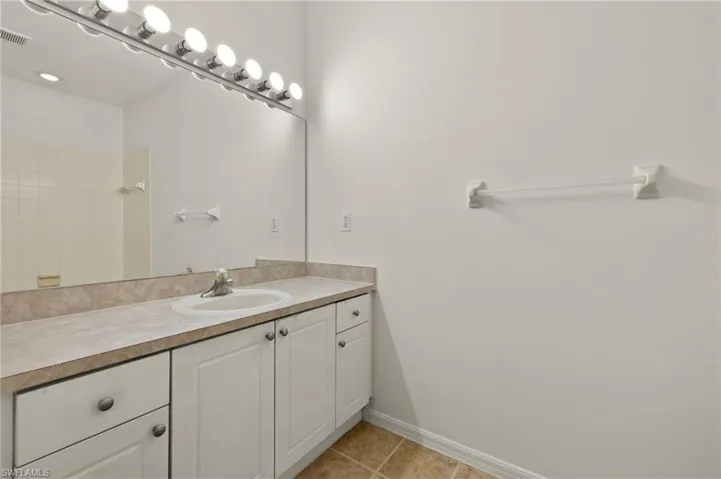 Bathroom featuring vanity, visible vents, baseboards, tile patterned flooring, and walk in shower