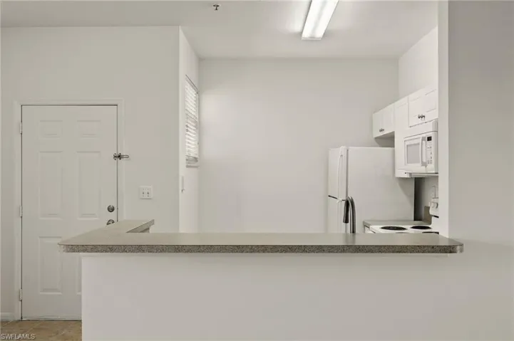 Kitchen featuring white appliances, a peninsula, and white cabinetry