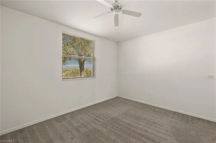 Carpeted spare room with ceiling fan and baseboards